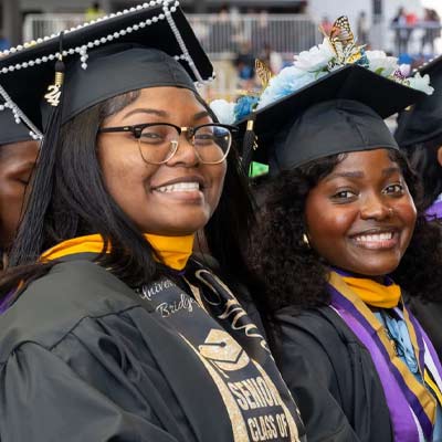 2 smiling graduates at Commencement
