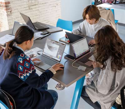 3 students sitting at a table on laptops