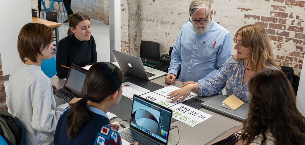 a student showing another student something on a laptop