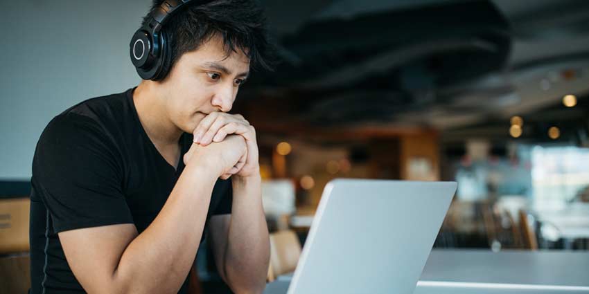 student wearing headphones studying at laptop