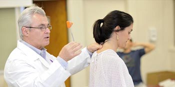 A chiropractic professor teaching a student at University of Bridgeport